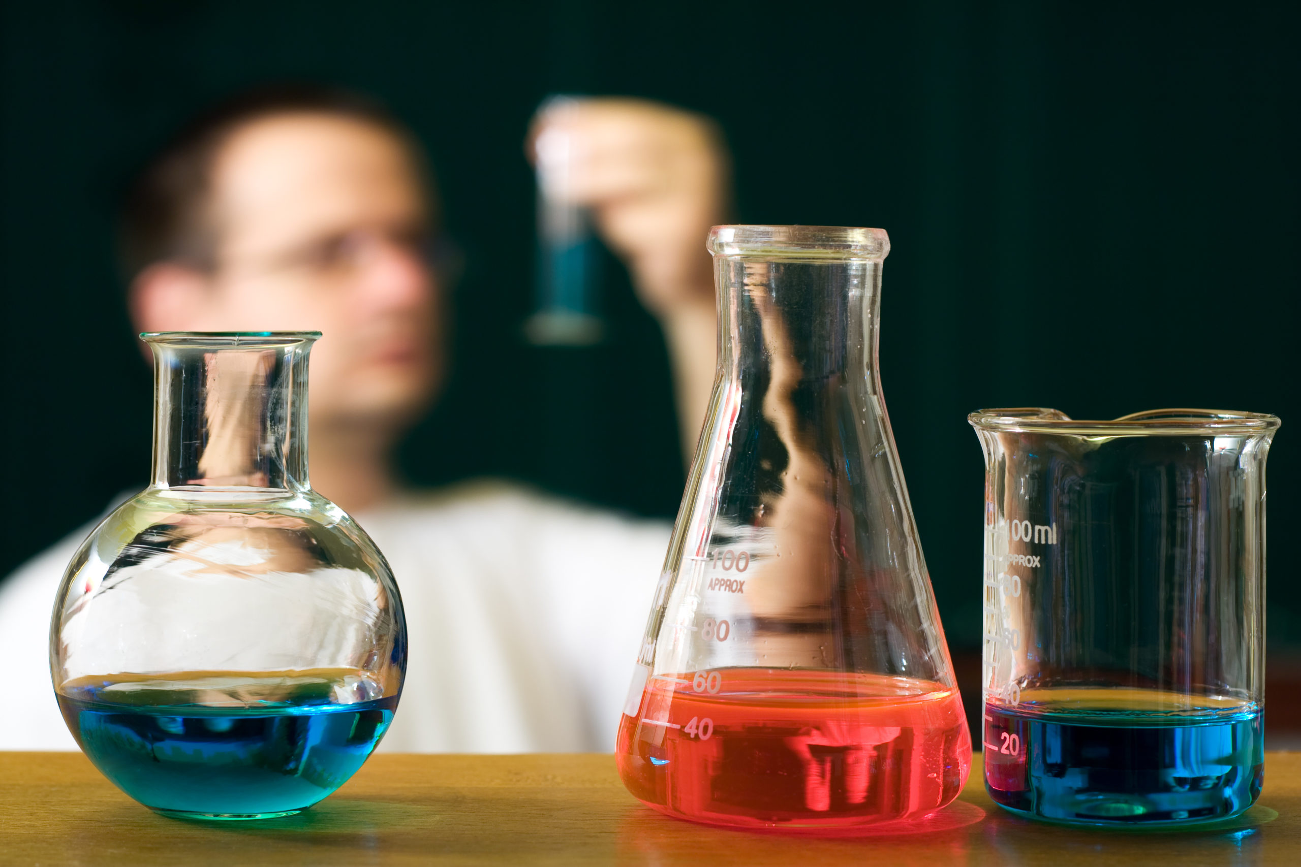 Chemistry research concept with flasks and a blurred scientist